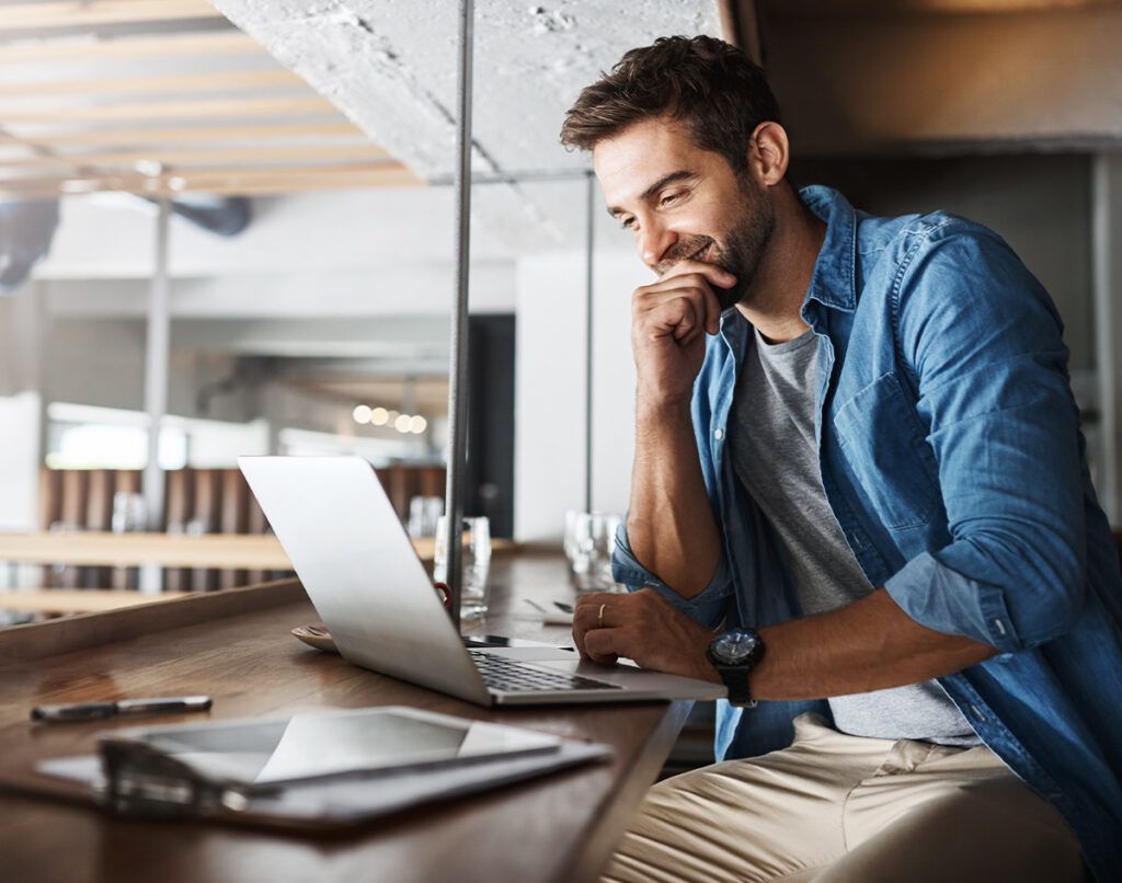 Mann arbeitet konzentriert am Laptop im Café als Symbol für AVGS Existenzgründer Coaching – TASys