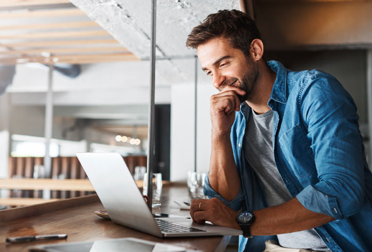 Mann arbeitet konzentriert am Laptop im Café als Symbol für Existenzgründercoaching bei TASys – TASys