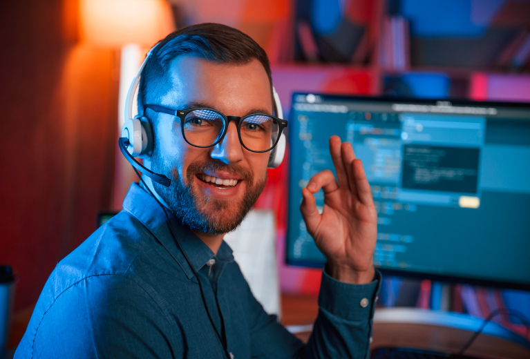 Mann mit Headset arbeitet am Computer mit Code Anzeige als Symbol für IT Weiterbildung bei TASys – TASys