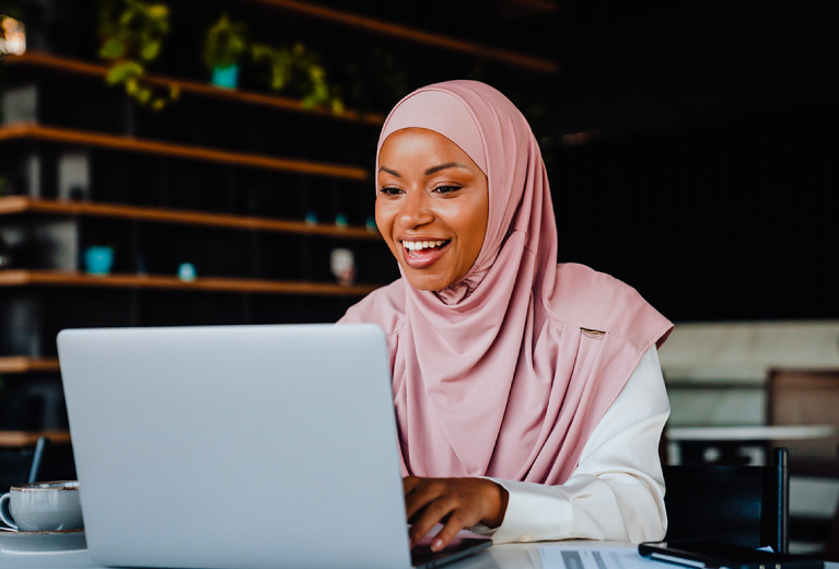 Frau arbeitet motiviert am Laptop in moderner Umgebung als Symbol für Inklusionscoaching bei TASys – TASys