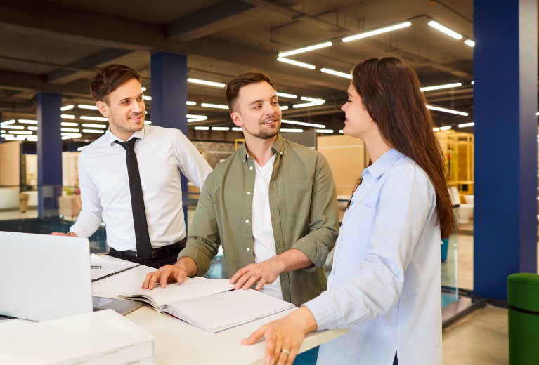Drei Personen im Gespräch mit Unterlagen im modernen Büro als Symbol für kaufmännische Berufe Weiterbildung bei TASys – TASys