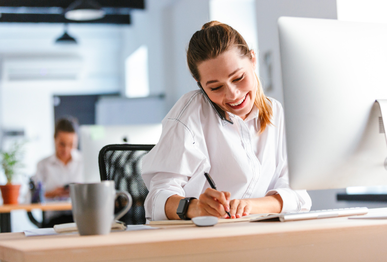 Frau telefoniert und macht Notizen am Computer im Büro als Symbol für Vorbereitungsangebote bei TASys – TASys