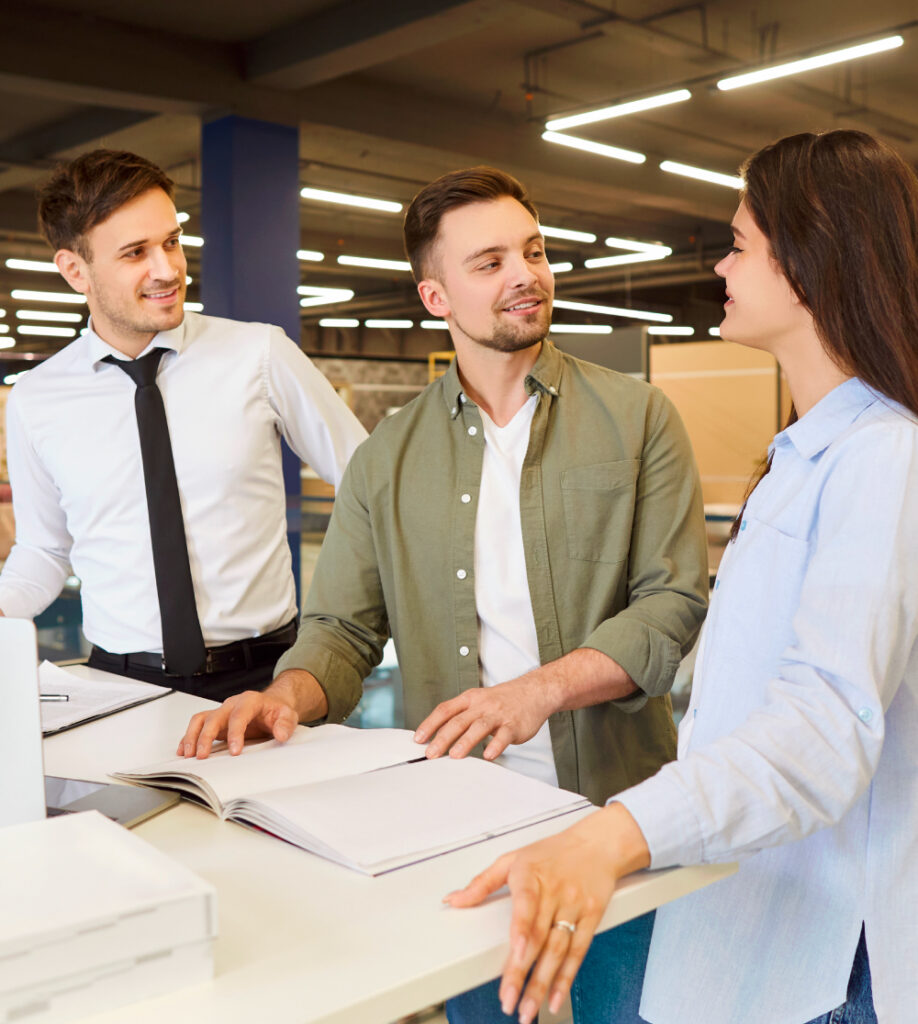 Drei Personen im Gespräch mit Unterlagen im modernen Büro als Symbol für kaufmännische Berufe Kursübersicht bei TASys – TASys