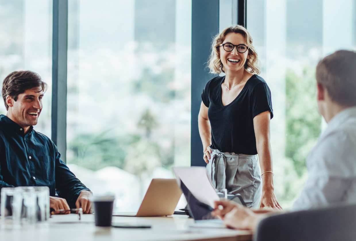Drei Fachkräfte im modernen Büro im Austausch bei einer Besprechung mit Laptop und Unterlagen – TASys