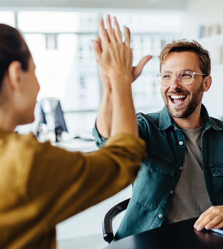 Zwei Personen geben sich ein High Five im Büro als Symbol für Teamgeist und Zusammenarbeit bei TASys – TASys